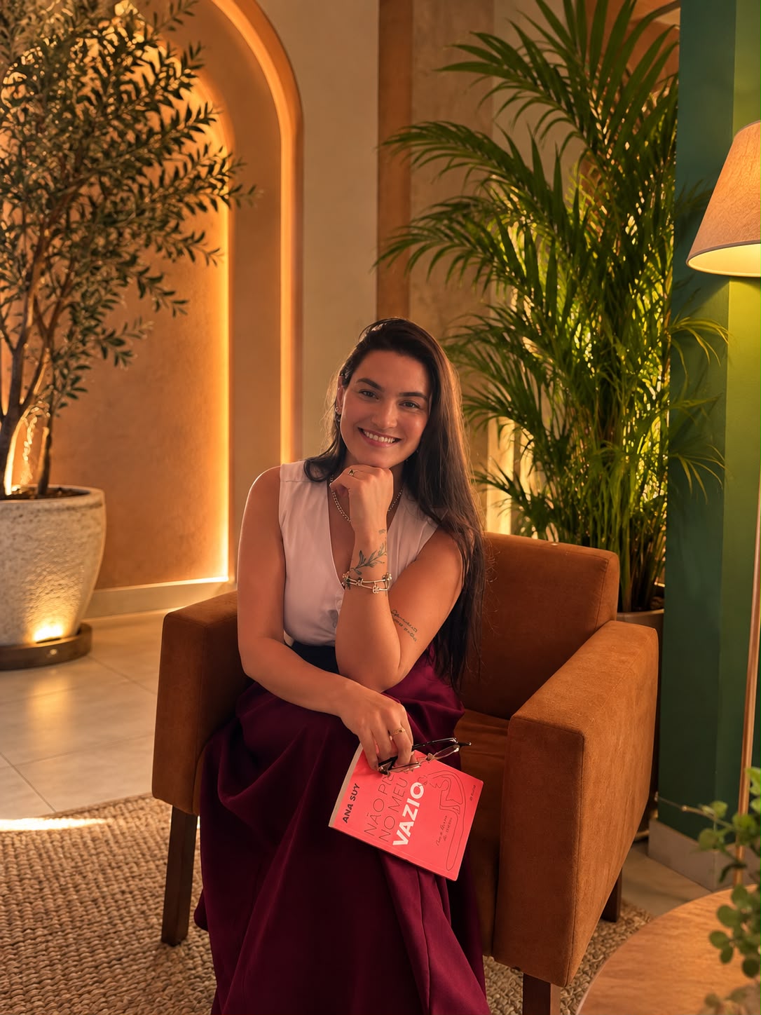 Lalesca Gonçalves em uma poltrona, com livro nas mãos